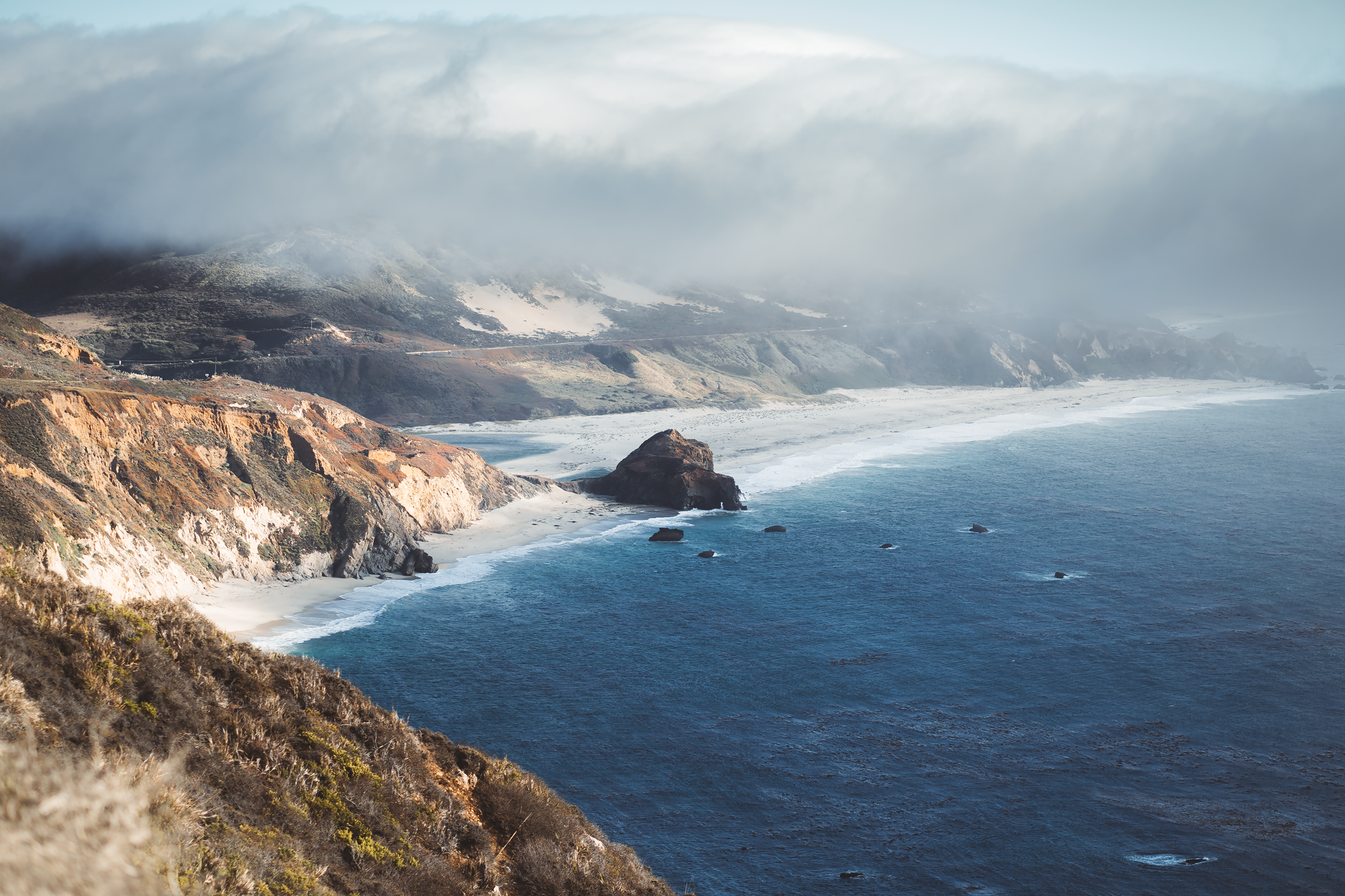Pacific ocean crashing against rocky cliffs along Big Sur highway